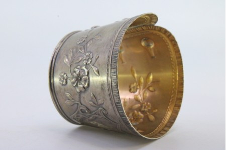 Argola de guardanapo em prata em forma de punho e relevada com motivos florais.